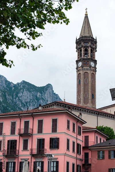 Fototapeta View over Lecco's traditional rooftops and the historic San Nicolò campanile, Lombardy, Italy. Classic Italian architecture set against a backdrop of the misty Prealpine mountains