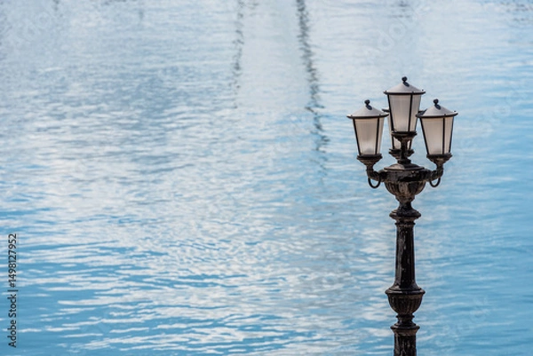 Fototapeta Typical retro street lamp with blue sea calm water on background on the seafront in Bari, Italy. Copy space