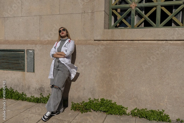 Fototapeta Confident doctor taking a break outside hospital, enjoying sunlight