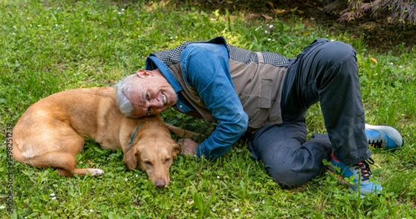 Obraz middle aged man lying in the grass of a park enjoying happy moments with his dog