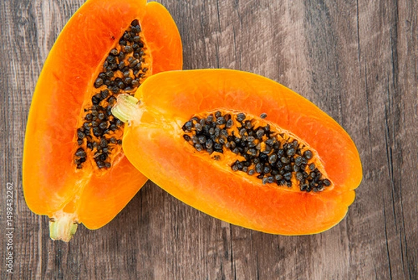 Obraz Papaya fruit on a dark wooden background. Slices of sweet papaya, Halved papayas
