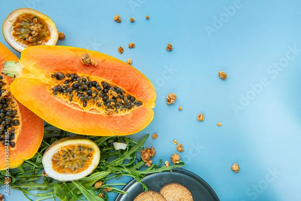 Obraz Papaya, passion fruit, rucola and granola on a blue background.