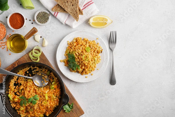 Obraz Red lentils dal in black pan and on plate on white table top. Lentils carrot and lettuce vegetarian meal, top view copy space