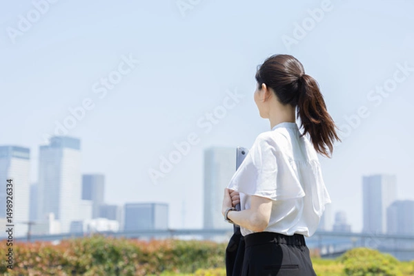Fototapeta 都会のビル群を見つめるビジネスウーマン