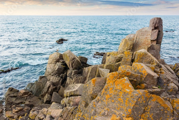 Fototapeta sea rock on the coast. travel nature background with stone on the shore. scenic destination. beautiful summer vacation at the seaside. calm surface of blue water and evening sky in seascape
