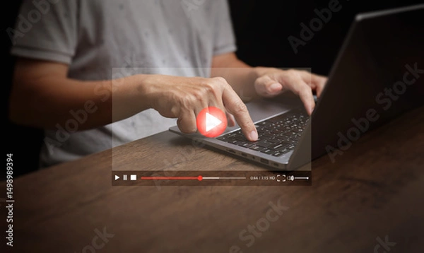 Fototapeta Watching online video is now embedded in everyday life. A man watches videos from his laptop computer for entertainment, including streaming movies, live shows, online lessons, and music