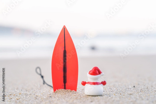 Fototapeta Sandy Christmas Snowman is watching the waves, standing on beautiful beach with a surf board - horizontal version in Patong Beach, Phuket, Thailand