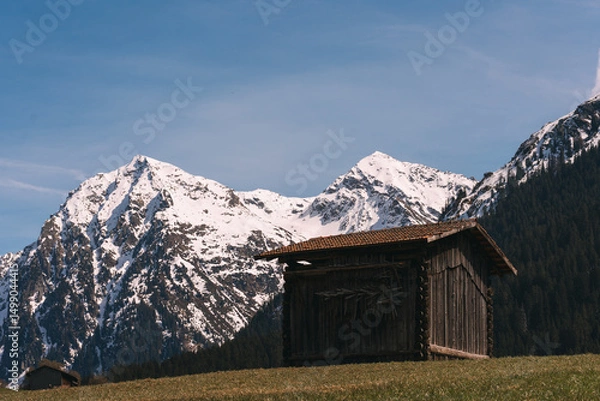 Fototapeta Old wooden barn overlooking majestic snow-capped mountains in the alps