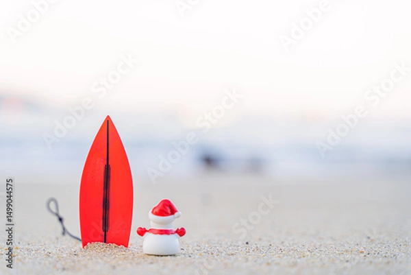 Fototapeta Sandy Christmas Snowman is watching the waves, standing on beautiful beach with a surf board - horizontal version in Patong Beach, Phuket, Thailand