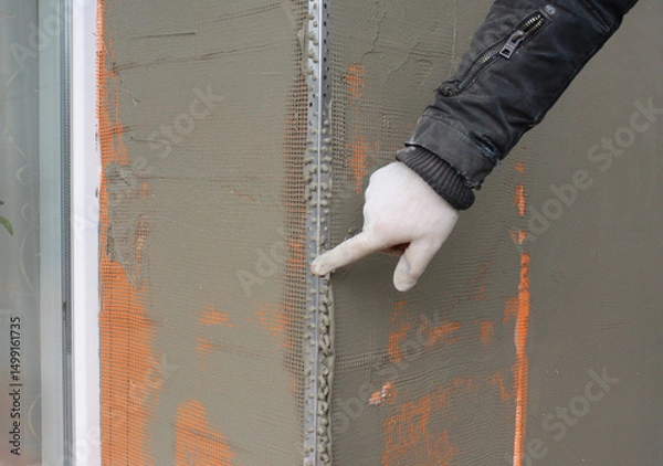 Fototapeta Window angle bead.  Close up on applying a coat of plaster, finish over the house window angle bead, reinforcing mesh outdoors.