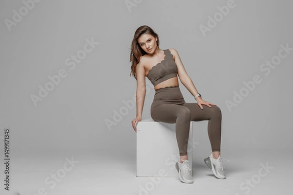 Fototapeta Model poses in stylish activewear on a minimalist set during a fashion shoot