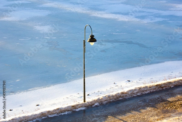 Obraz Lamppost, a light fixture in a waterfront park. Electric lamp near the sidewalk.
