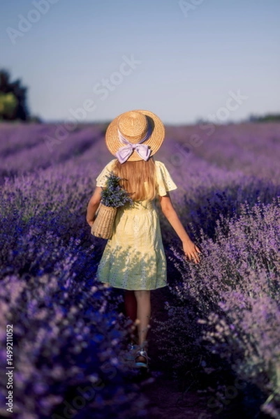 Obraz girl child in a yellow dress and a straw hat in a field of lavender