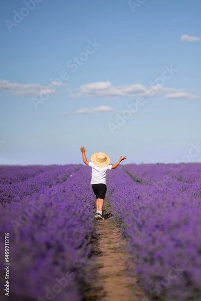 Obraz A boy in a hat runs into a field of lavender. Provence