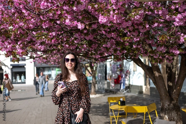 Fototapeta Young woman against the background of a sakura tree