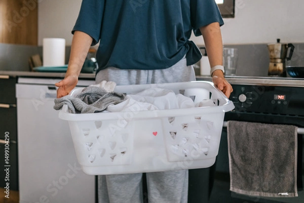 Obraz Young woman drying laundry on balcony during slow morning at home. Real moment, Gen Z lifestyle, sustainability, calm domestic routine, mindful living, eco-conscious habits, natural light.