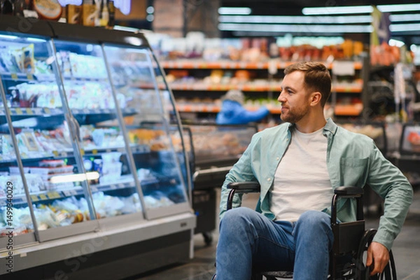 Fototapeta Customer using wheelchair choosing groceries in supermarket refrigerator