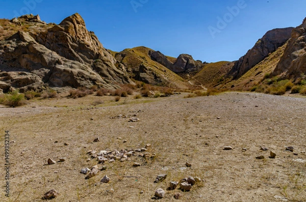 Fototapeta Massive Rock Formation in Dry Mountain Valley under Clear Deep Blue Sky with Sparse Vegetation