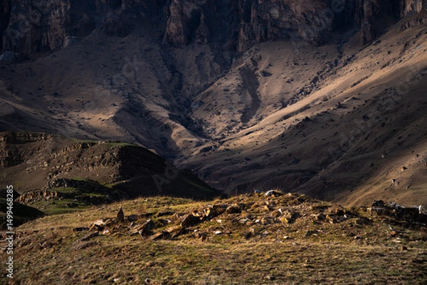 Obraz Rocky lawn against the backdrop of high rocks with rays of the setting sun. Landscape without sky
