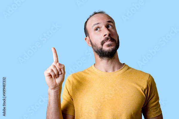 Fototapeta young man pointing finger up to copy space, having an idea