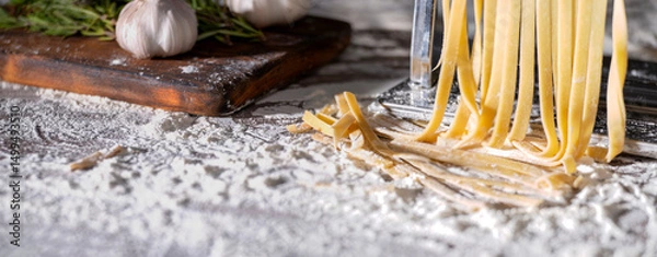 Obraz Fresh raw noodles made on home pasta machine on kitchen table low angle view