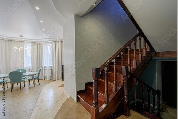 Fototapeta well-lit interior showcases a wooden staircase leading to a second floor, alongside a dining area with aqua chairs and white curtains.