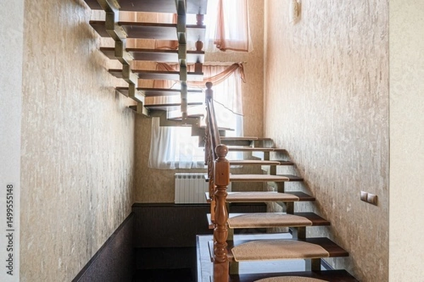 Fototapeta detailed view of a wooden staircase with carpeted treads, showing the craftsmanship of the balusters and handrail against a textured wall