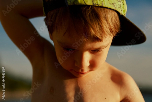 Fototapeta Portrait of a little cute boy in a cap by the sea in summer.