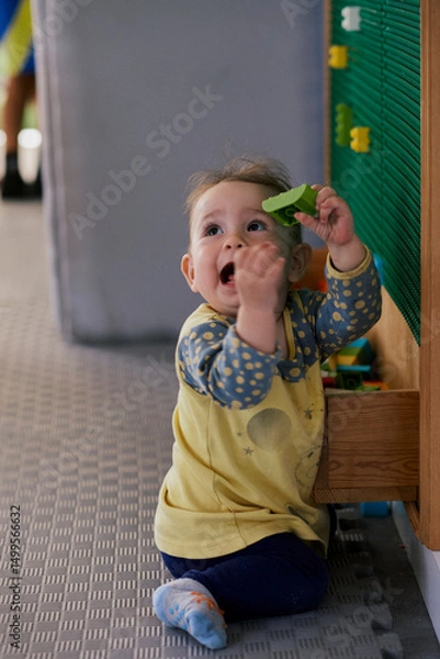Fototapeta Little girl playing the constructor in the kid indoor  playground.