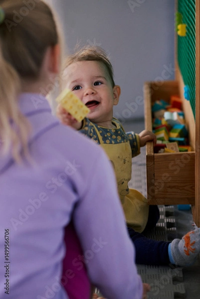 Fototapeta Little girl playing the constructor in the kid indoor  playground.