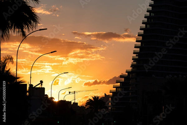 Obraz Sunset over Limassol city with modern buildings and construction crane silhouetted against vibrant evening sky