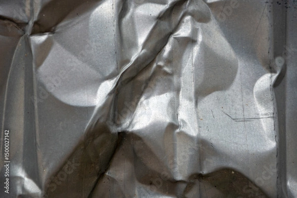 Fototapeta Crumpled metal surface reflecting light in unique patterns