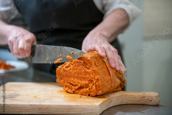 Fototapeta Close-up of hands cutting salami and prosciutto with a sharp knife for a charcuterie plate