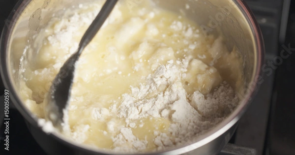 Fototapeta Handheld shot of mixing flour with butter mix for making choux dough, 4k photo