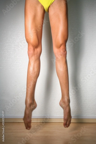 Fototapeta Cropped shot of woman's long legs, while jumping with fully extended with pointed toes. Unrecognisable woman showing her sporty muscular legs, dancer, ballerina, gymnast  jump