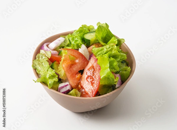 Fototapeta Vegetarian salad with cucumbers, tomatoes and red onion. Vegan salad in a beige deep plate isolated on a white background. Top view