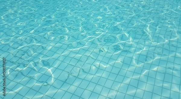 Fototapeta Pristine blue water of a swimming pool, highlighting the clean, tiled floor through its ripples.
