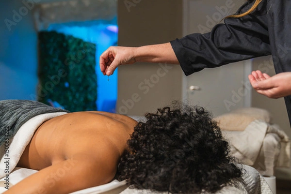 Fototapeta Therapist dripping essential oils on patient's back during a relaxing massage therapy session in a modern physiotherapy center, promoting wellness and relaxation