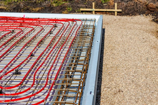 Obraz Underfloor heating system with red pipes on construction site, Close-up of underfloor heating installation using red pipes laid on a foundation grid at a building