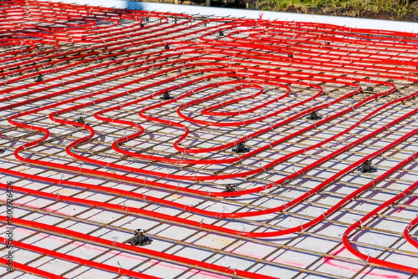 Obraz Underfloor heating system with red pipes on construction site, Close-up of underfloor heating installation using red pipes laid on a foundation grid at a building