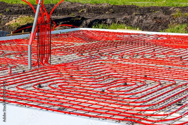 Obraz Underfloor heating system with red pipes on construction site, Close-up of underfloor heating installation using red pipes laid on a foundation grid at a building