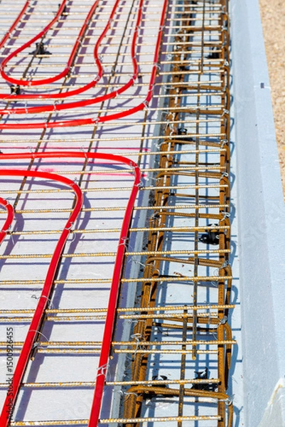 Obraz Underfloor heating system with red pipes on construction site, Close-up of underfloor heating installation using red pipes laid on a foundation grid at a building