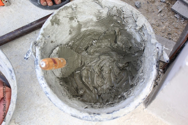 Obraz Bucket filled with wet cement and a trowel at construction site