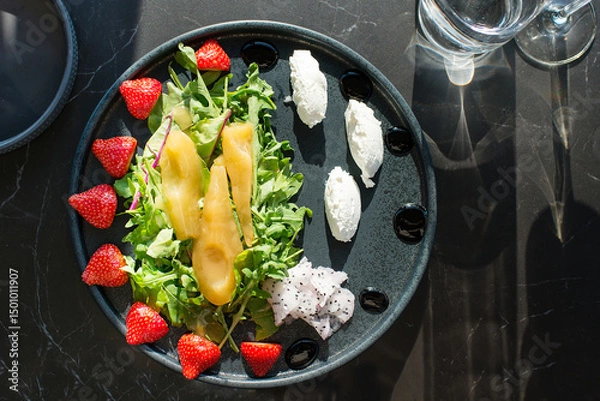 Obraz Fresh sweet Pears salad with microgreens, strawberries, pitahaya, and white soft cheese on a black plate	