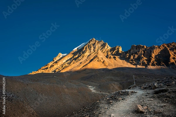 Obraz Trekking route to Thorung La pass against illuminated by rising sun Yakwakang peak. Annapurna circuit trek, Nepal.