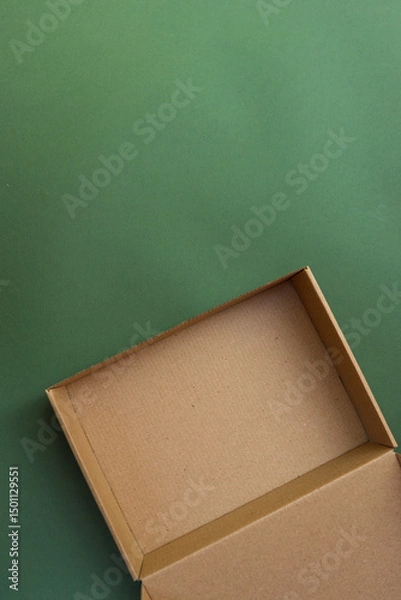 Obraz Empty brown cardboard gift box placed on a solid green background. Eco-friendly packaging concept with minimalist, natural aesthetic and copy space