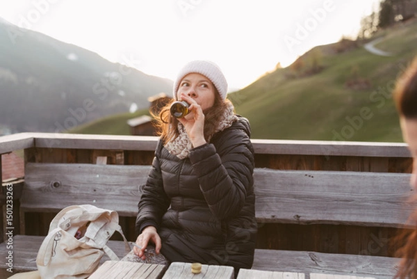 Fototapeta Tourist drinking beer enjoying mountain view at sunset