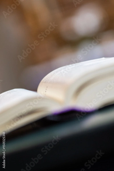 Fototapeta An open holy book rests at the front, gazing out over the church, where the chandelier glimmers above the nave