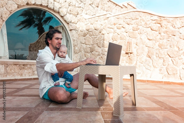 Fototapeta dad and his little son with a laptop are resting and working as a freelancer on vacation