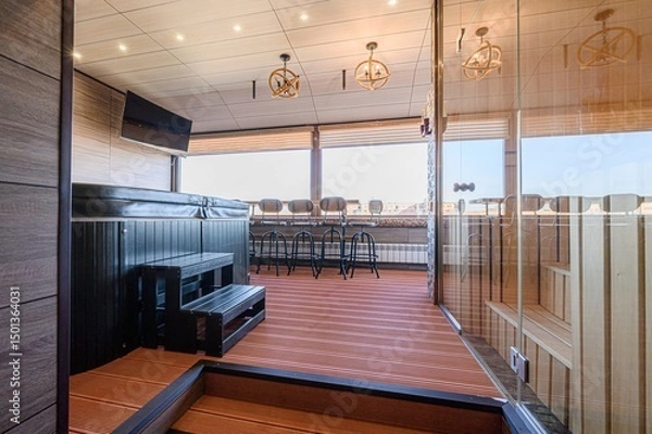 Fototapeta modern wellness space with a hot tub, sauna, and a bar area with stools overlooking a cityscape through large windows. The interior features wood paneling, stylish lighting, and tiled accents.